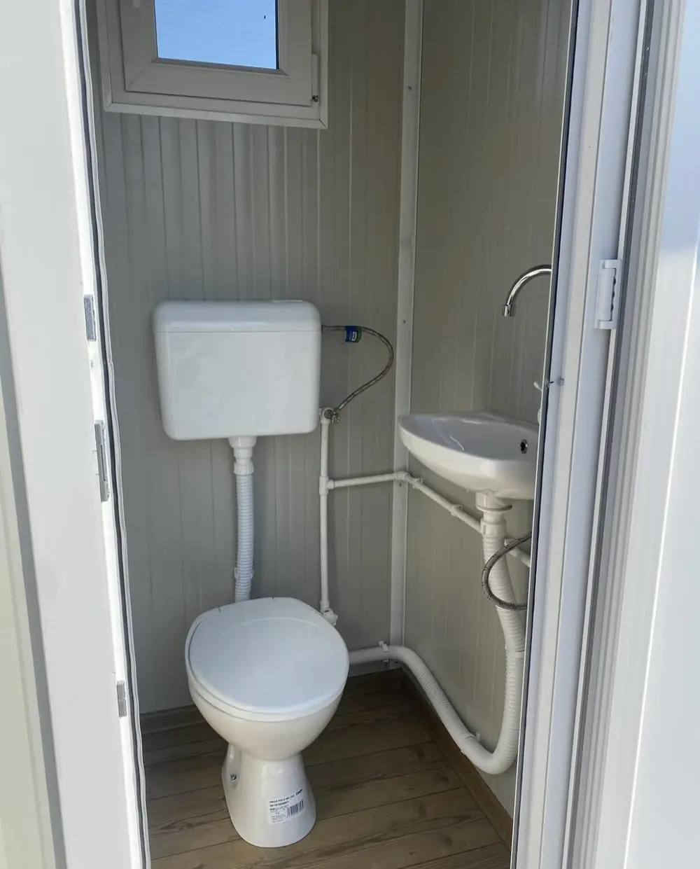Cabin-style restroom interior with flush toilet and corner sink