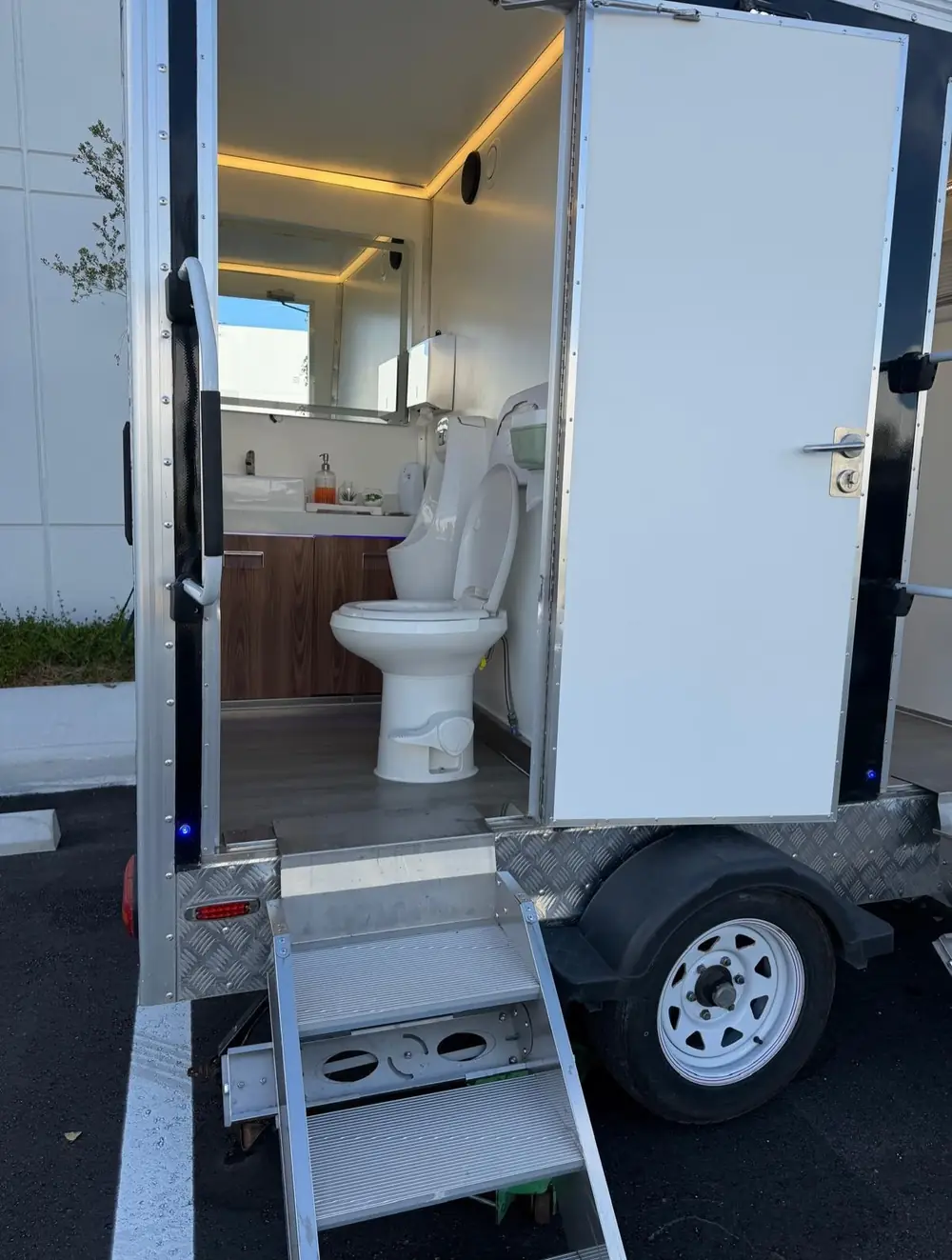 Luxury restroom trailer interior with toilet and wood vanity