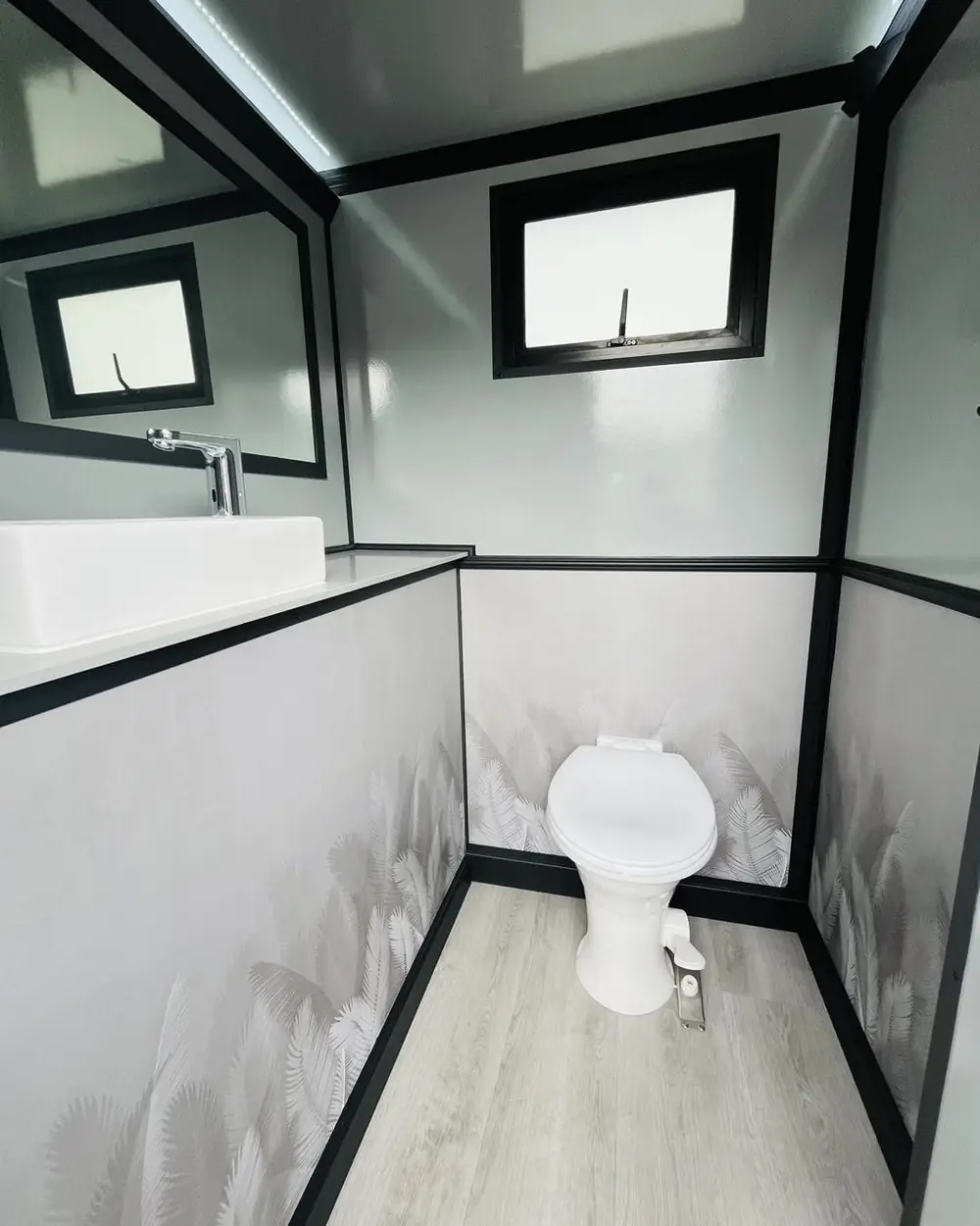 Modern restroom trailer stall with vanity and toilet